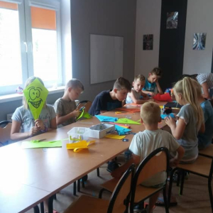 Grupa dzieci siedzących wokół stołu z balonem. 