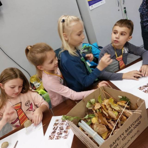 Grupa dzieci wokół stołu z jedzeniem. 