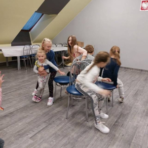 Grupa dzieci siedzących na krzesłach. 