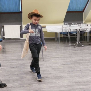 Dziecko w kapeluszu i chodzące po drewnianej podłodze. 