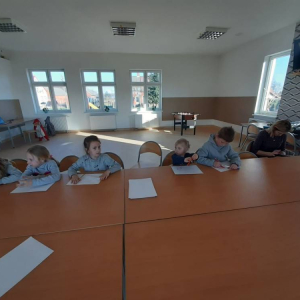 Grupa dzieci siedzących w pokoju. 