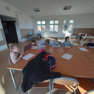 Grupa ludzi siedzących przy stole w klasie. 