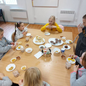 Grupa dzieci jedzących przy stole. 