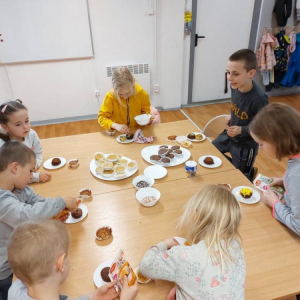 Grupa dzieci jedzących przy stole. 